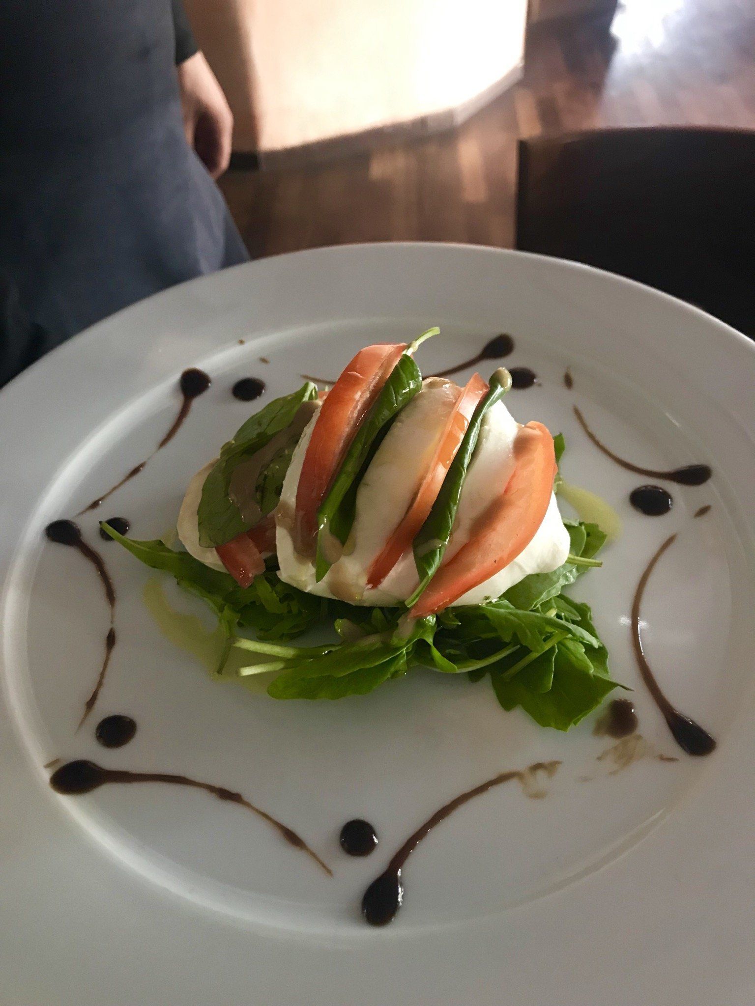 Ein weißer Teller mit einem Salat aus Tomaten und Mozzarella