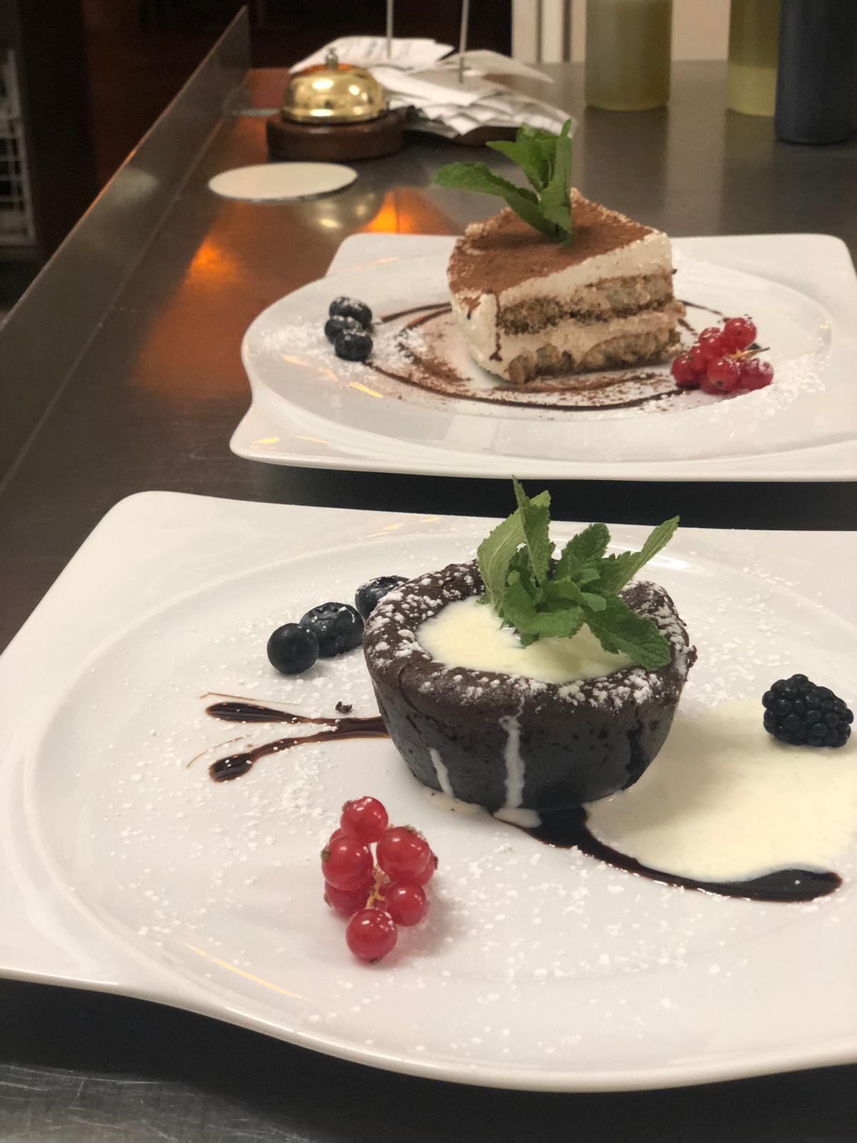Zwei weiße Teller mit Desserts darauf auf einer Theke