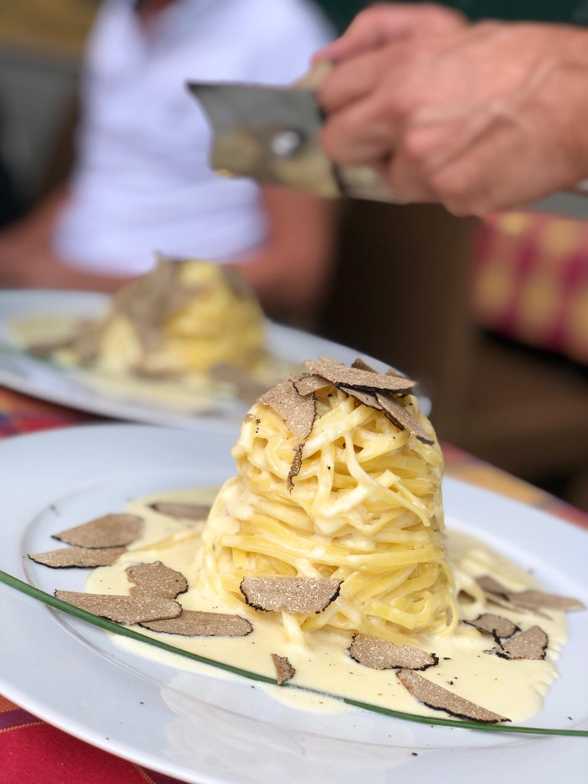 Eine Person macht ein Foto von einem Teller Spaghetti mit Trüffel obenauf.