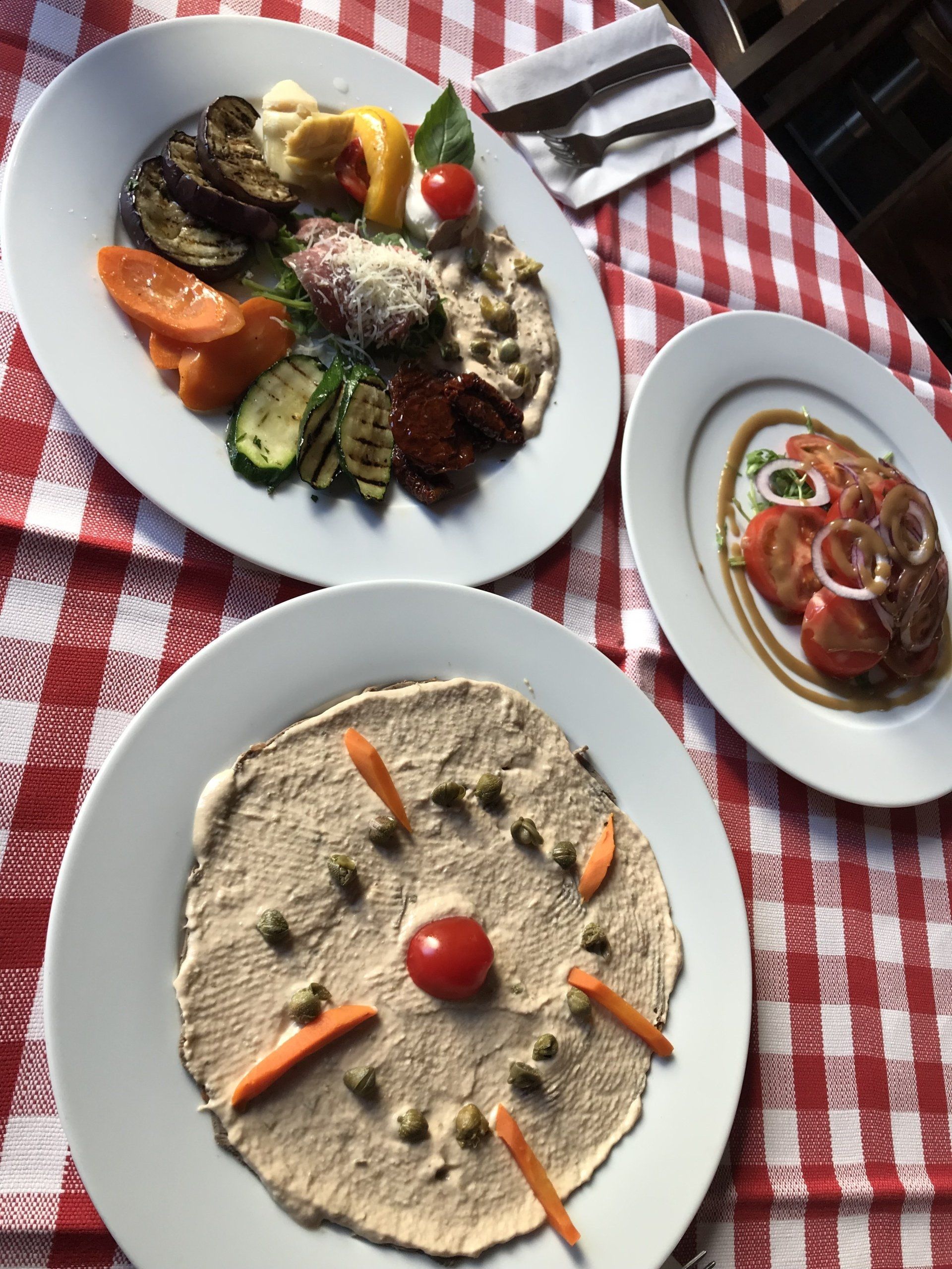 Drei Teller mit Essen auf einer karierten Tischdecke