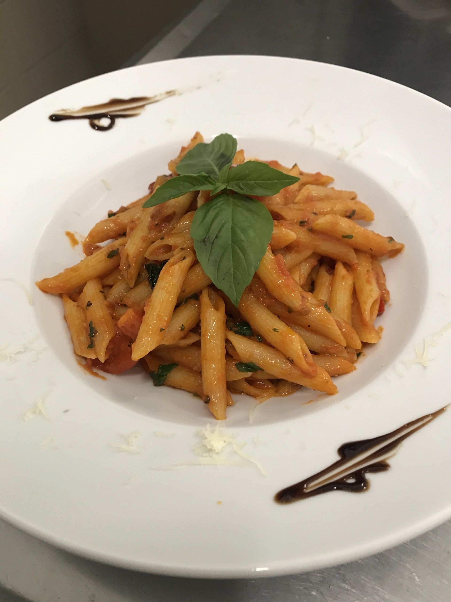 Ein Teller Nudeln mit Tomatensauce und Basilikum obenauf