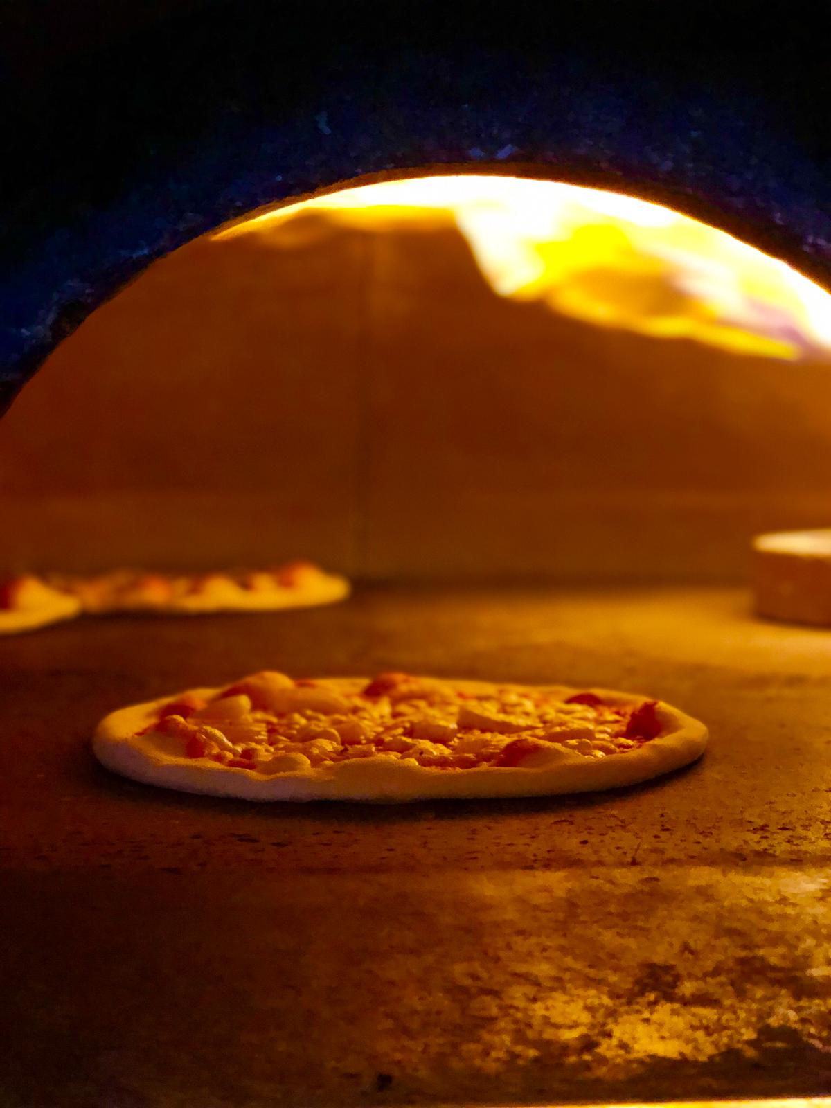 In einem Ofen wird eine Pizza gebacken, aus dem Flammen schlagen.