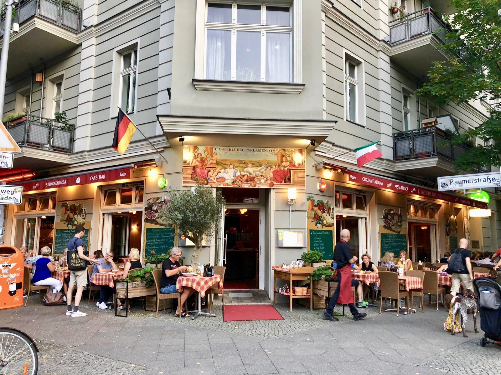 Eine Gruppe von Leuten sitzt an Tischen vor einem Restaurant.