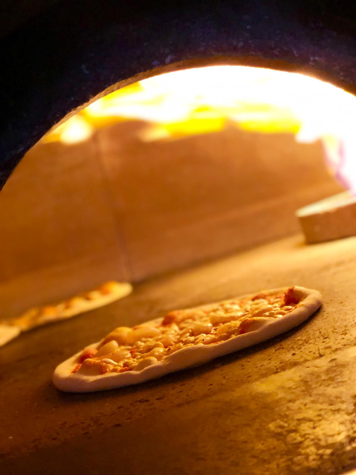 In einem Ofen wird eine Pizza gebacken, aus dem Flammen schlagen.