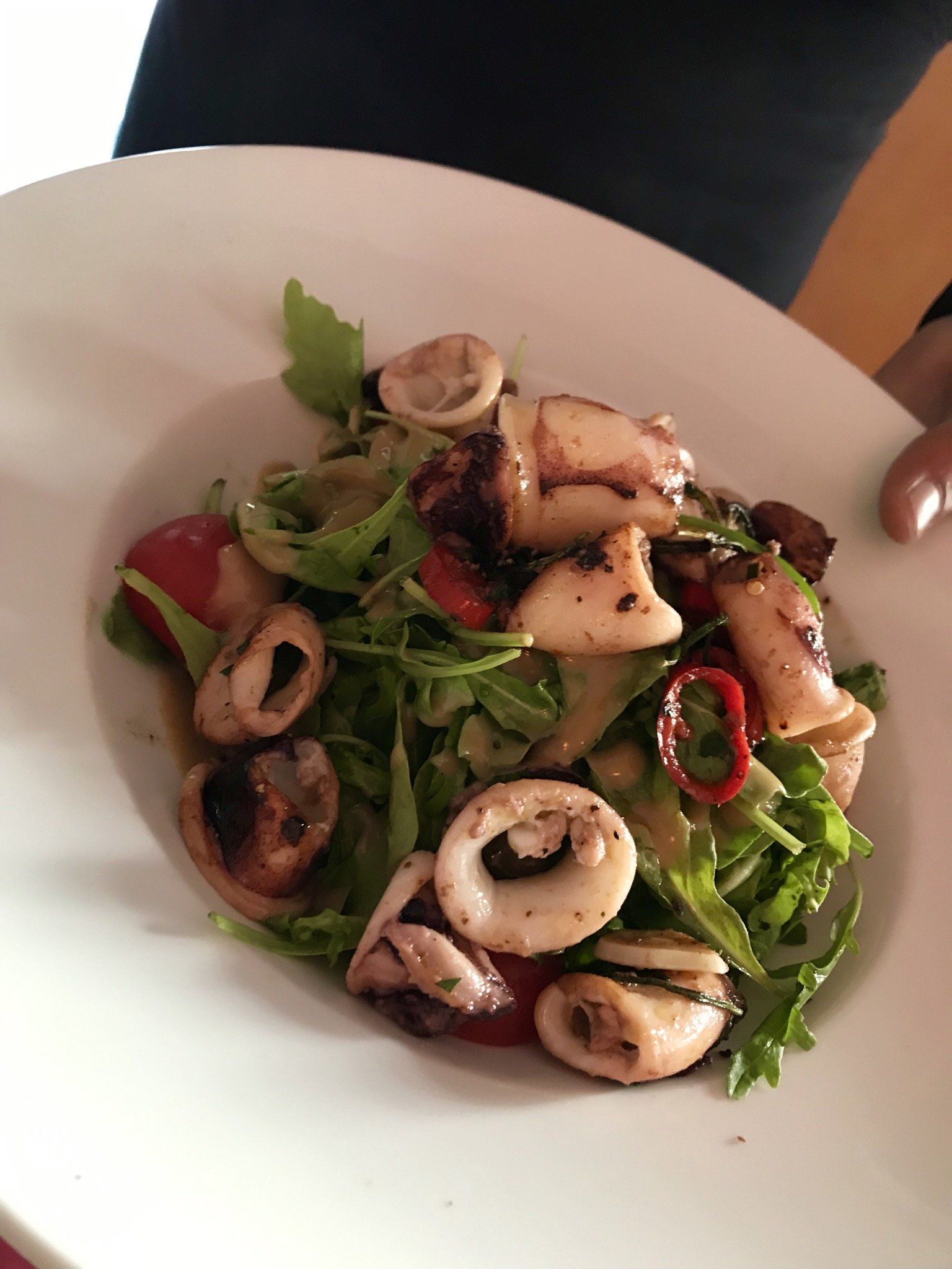 Ein weißer Teller mit einem Salat aus Tintenfisch und Gemüse