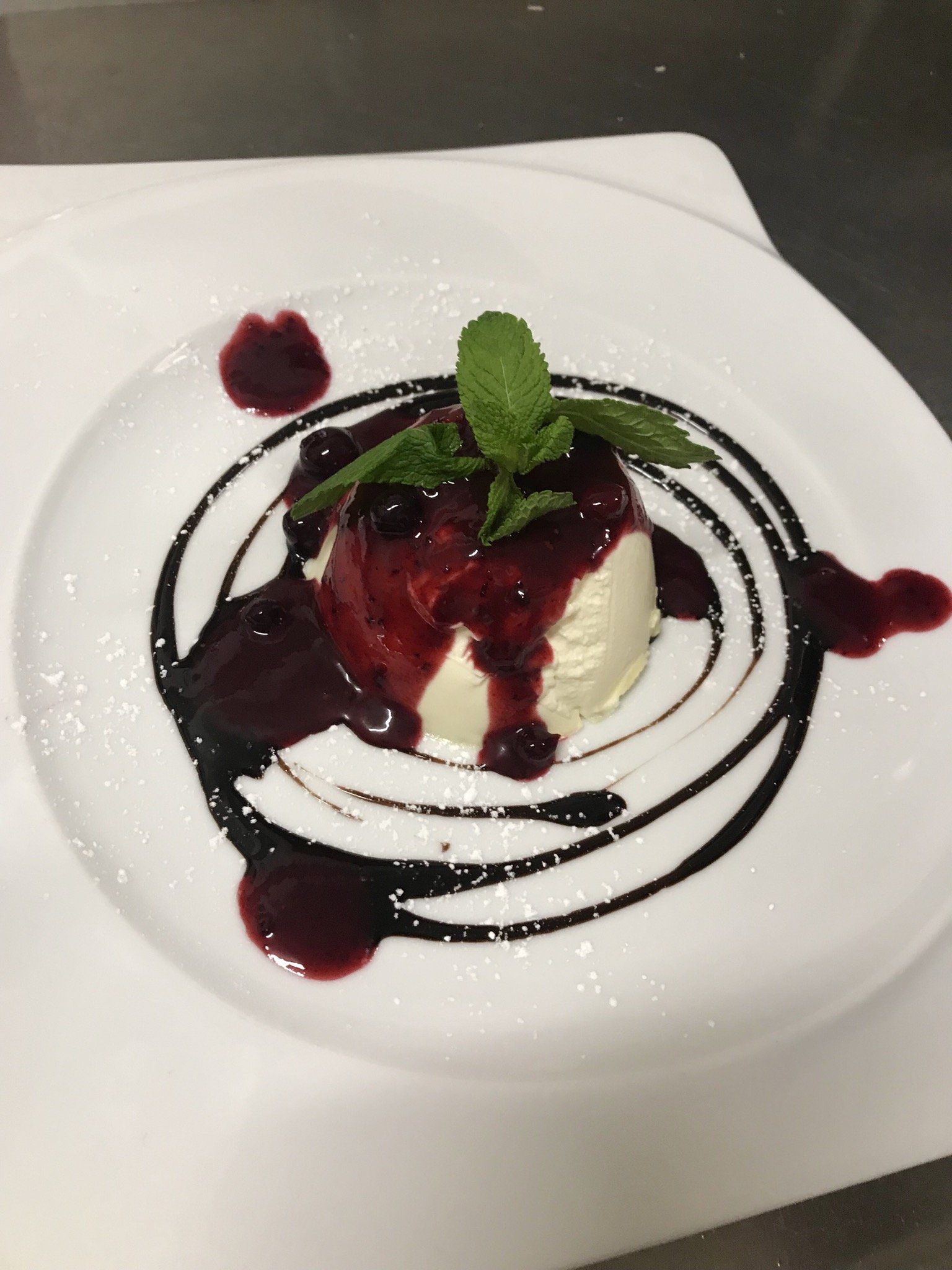 Ein weißer Teller mit einem Dessert und einem Minzblatt darauf