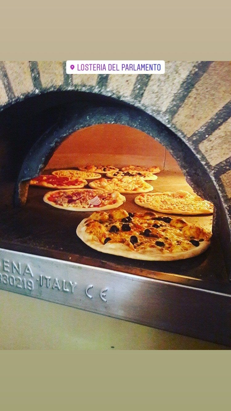 In einem Pizzaofen werden drei Pizzen gebacken.