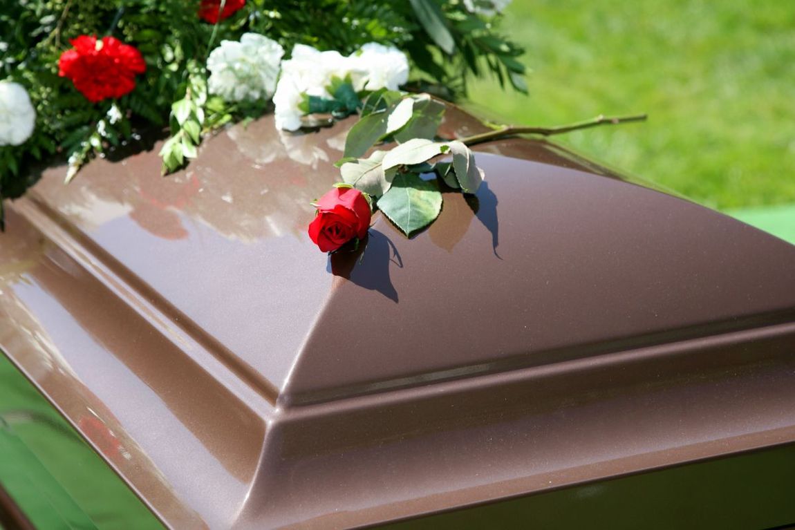 Cassa funebre in legno con composizione di fiori freschi