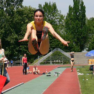 Eine Frau springt auf einer Strecke in die Luft