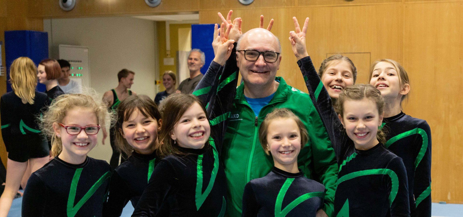 Eine Gruppe junger Mädchen posiert für ein Foto mit einem Mann in einer grünen Jacke.
