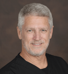 Dr. Kenneth L. Reed - Course Director A man with gray hair and a beard is wearing a black shirt and smiling.