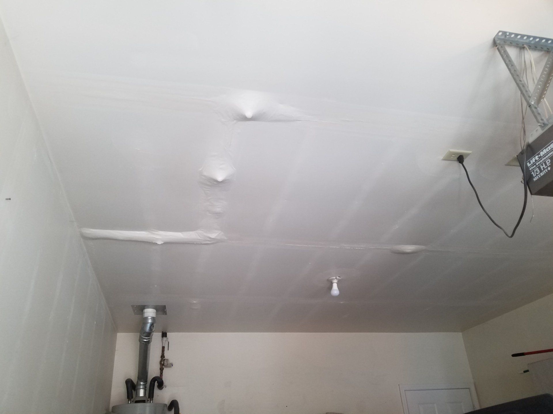 A white ceiling in a garage with a ladder hanging from it.