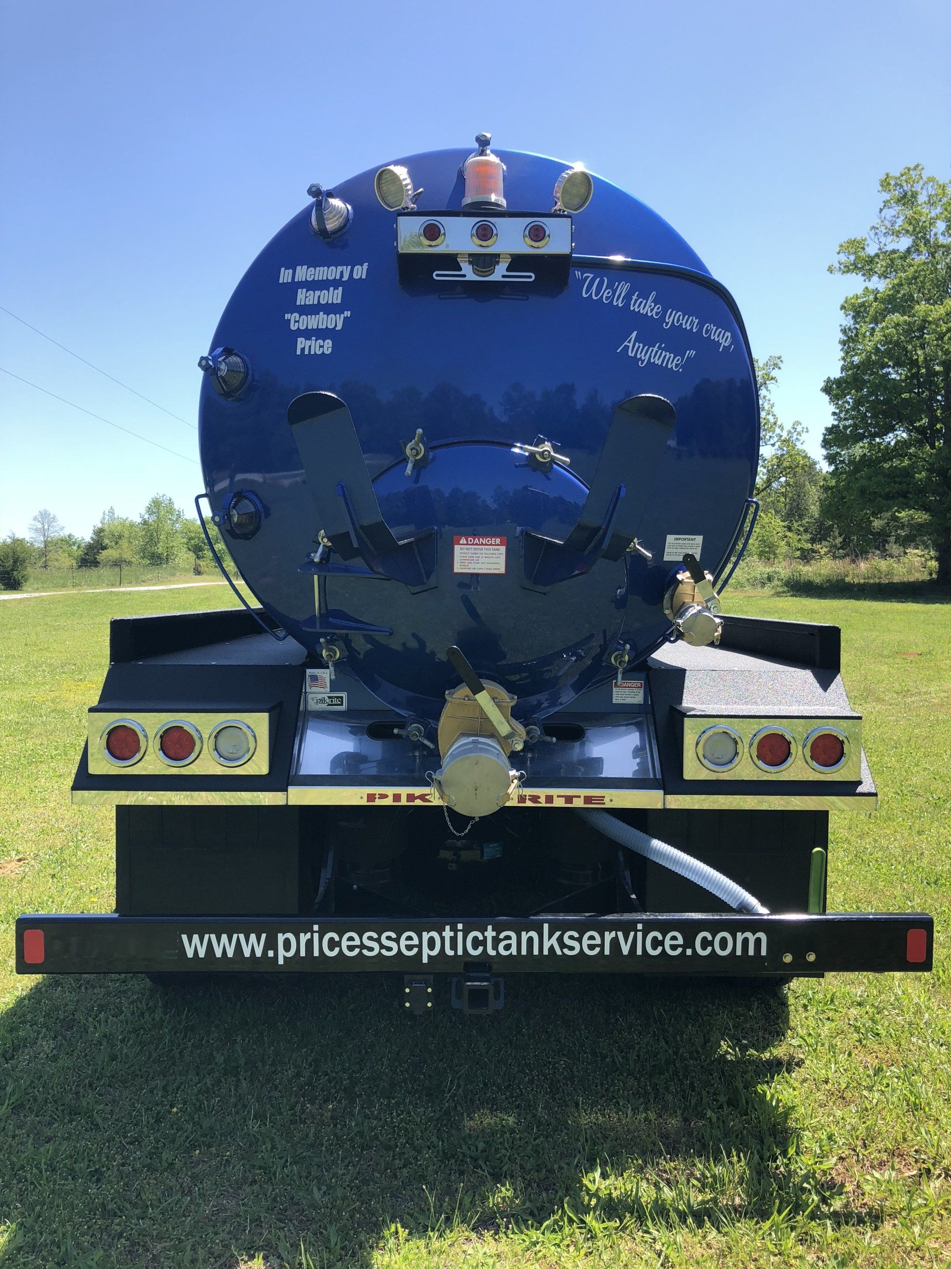 Blue septic tank truck on green grass with the website address www.princesseptictankservice.com on the bumper.