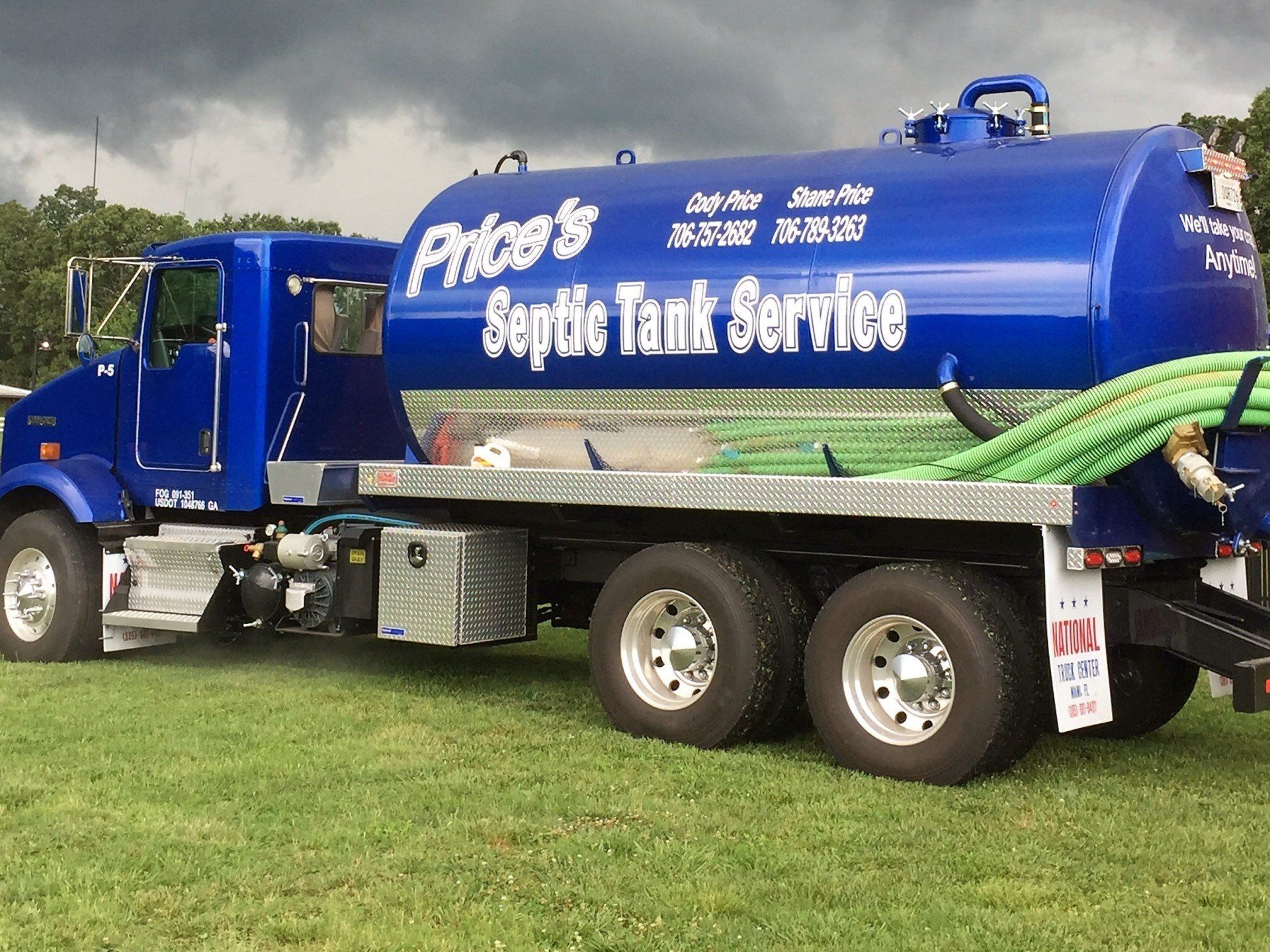 Blue septic tank truck on green grass, Price's Septic Tank Service, cloudy sky.