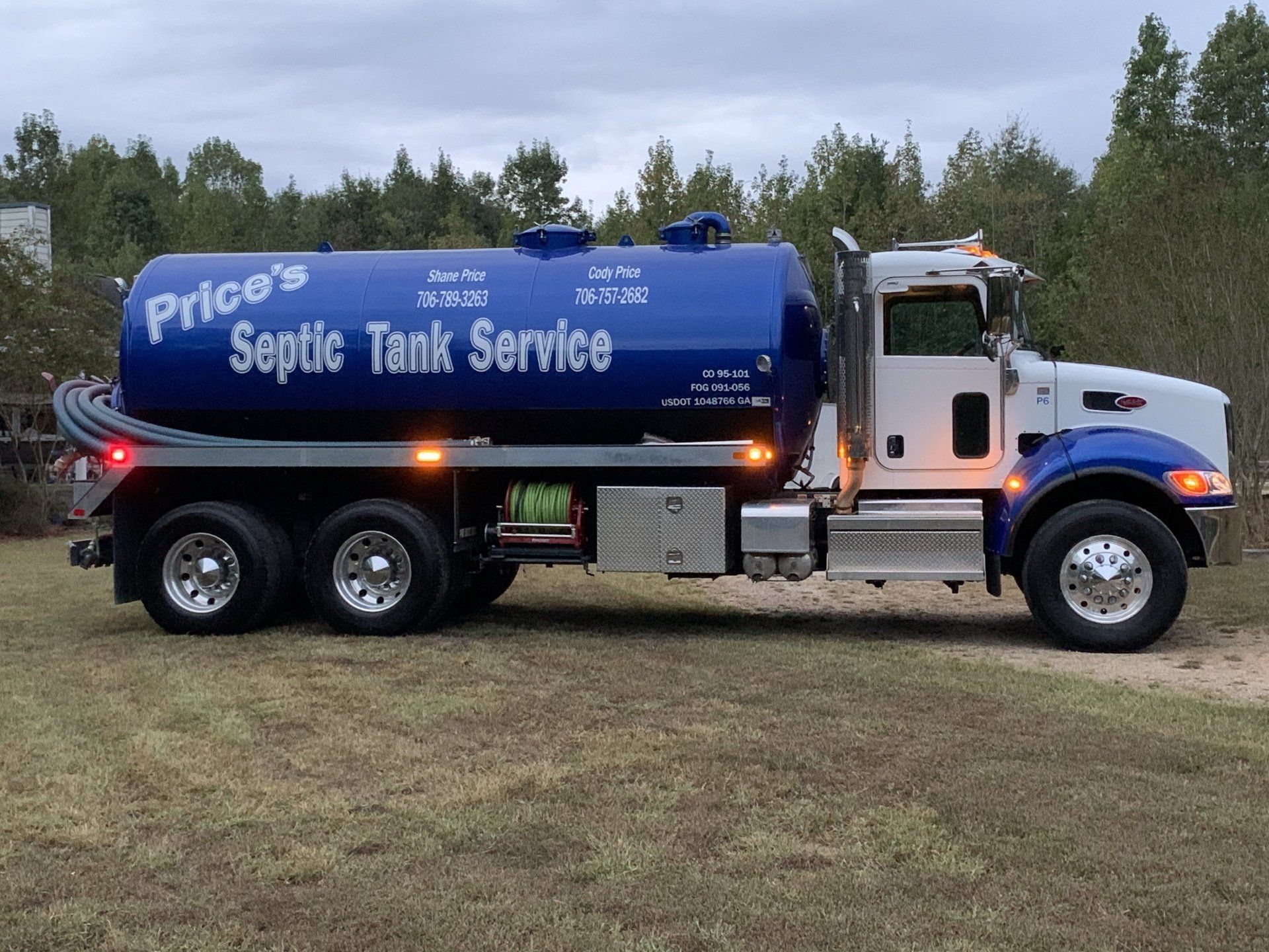 Price's Septic Tank Service truck, blue tank, white cab, parked on grass.