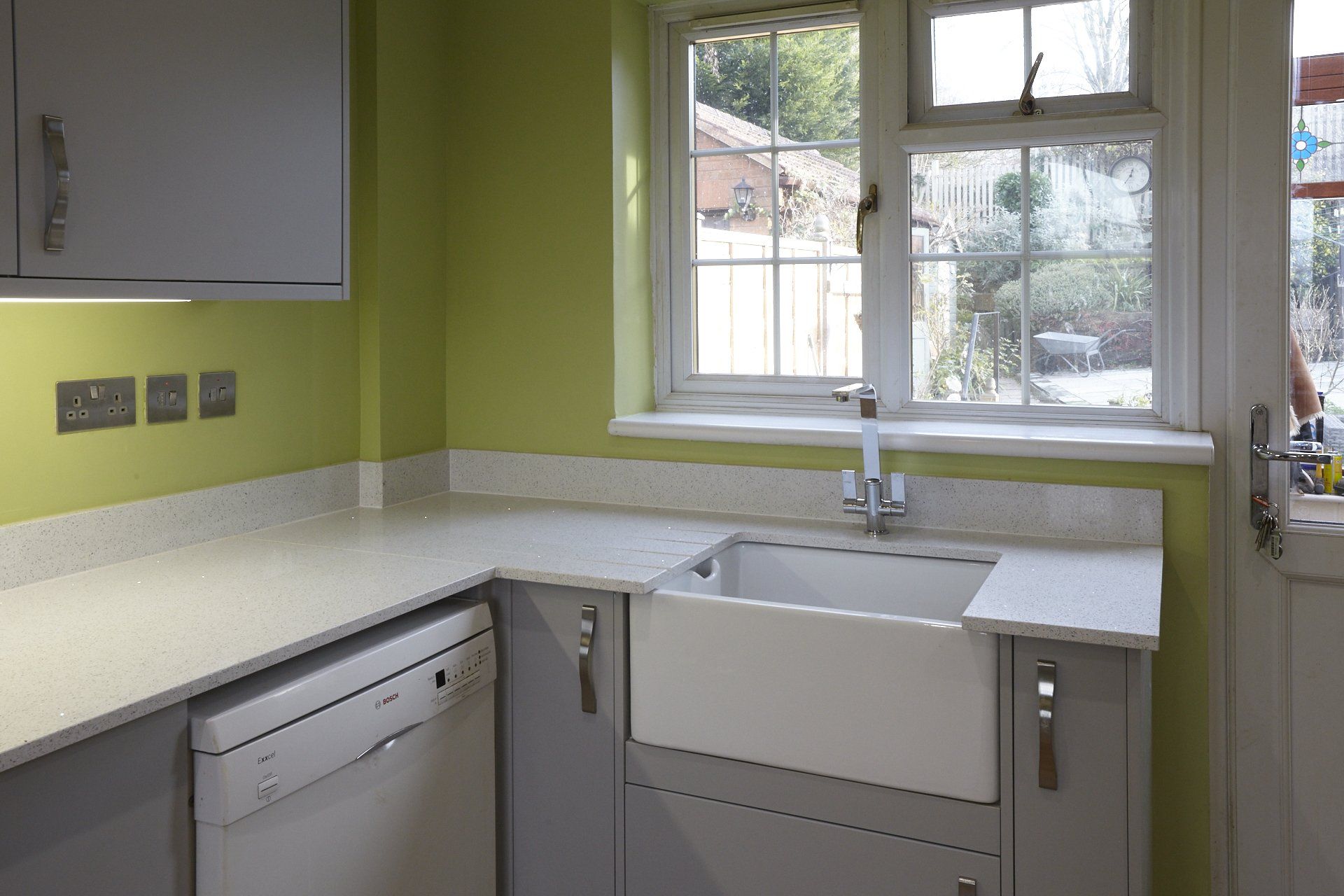 A kitchen with a sink , dishwasher , and green walls.