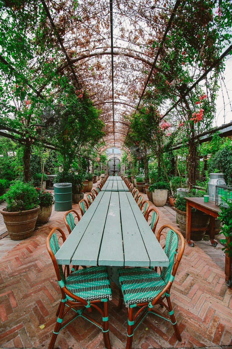 A Long Table and Chairs in A Greenhouse Surrounded by Plants — All Round Ground Maintenance in Woolgoolga, NSW