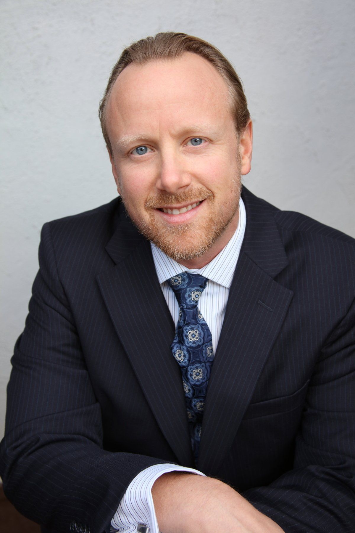 A man in a suit and tie is smiling for the camera.