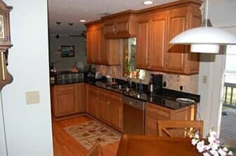 Small Kitchen — kitchen remodeling services in Newport News, VA A kitchen with light wood cabinets, dark granite countertops, stainless steel appliances, and wood flooring.
