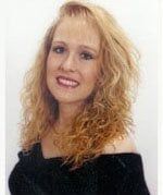 Tina Paynter—General Contractor in Newport News, VA Portrait of a smiling person with shoulder-length, wavy blonde hair wearing a black off-the-shoulder top.