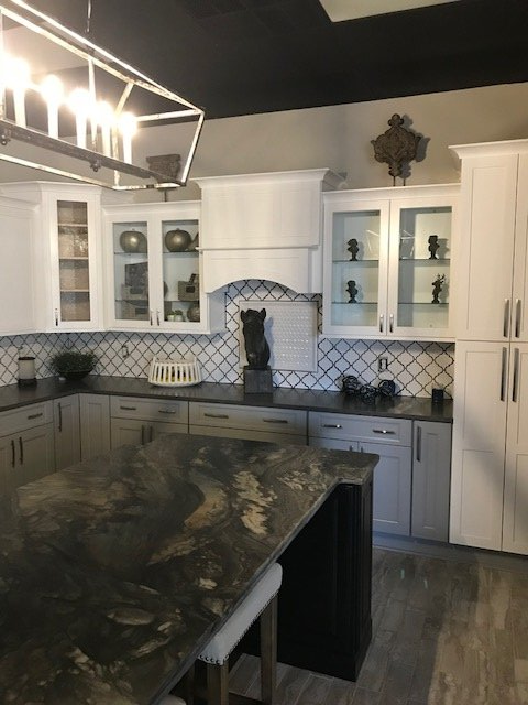 A modern kitchen featuring white cabinets, dark countertops, a black ceiling, and a large hanging light fixture.