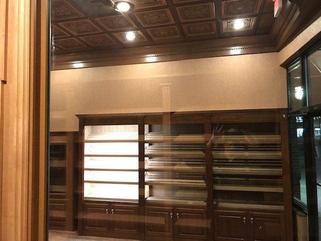 An interior view of a room with dark wood shelving, cabinets, and a decorative, paneled ceiling with recessed lighting.