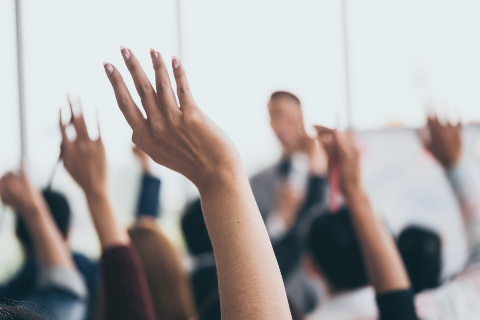 A group of people are raising their hands to answer a question.