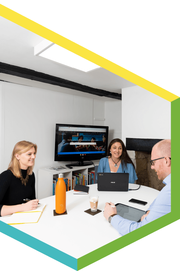 A group of people are sitting around a table with laptops.