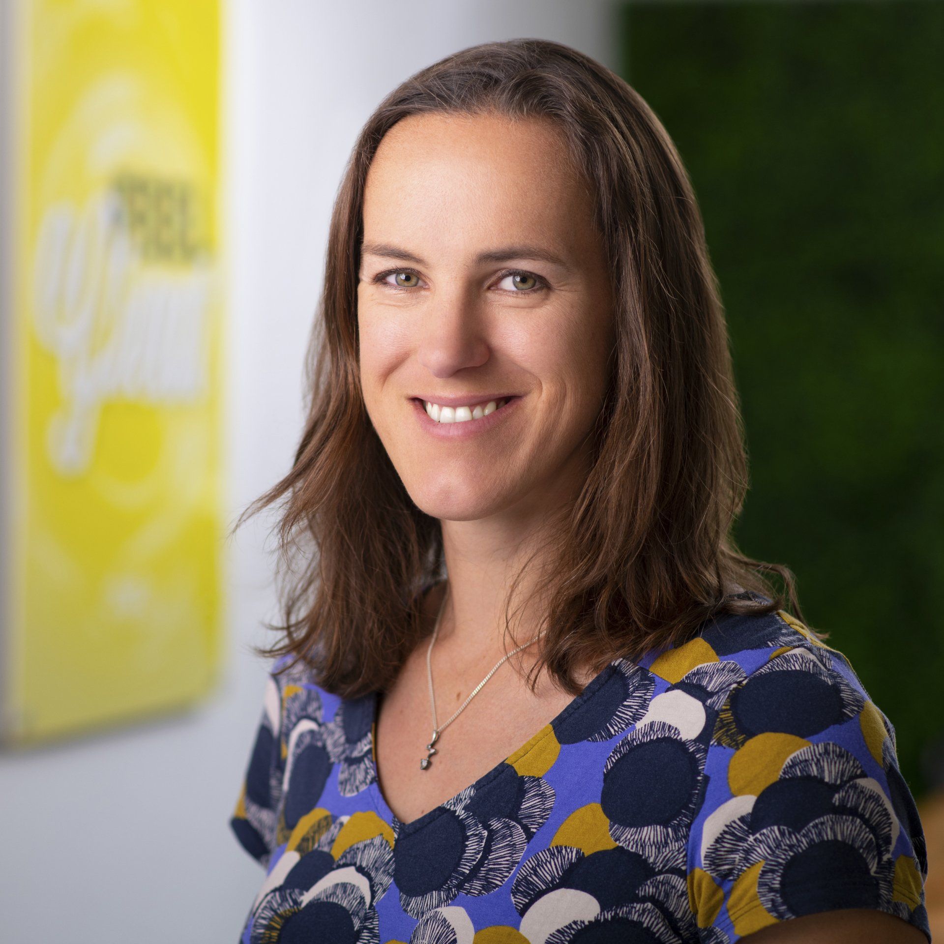 A woman in a blue and yellow shirt is smiling for the camera.