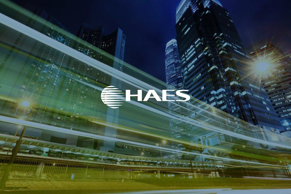 A blurry picture of a city at night with a haes logo in the foreground.