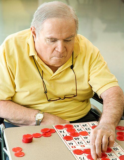 Man in yellow shirt playing a red and white board game at a table