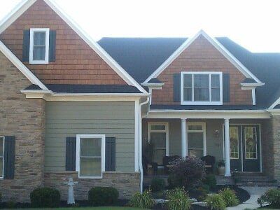 Suburban house with stone and shingle exterior, front porch, and large windows