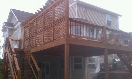 Wooden elevated deck and staircase attached to a house, with lattice railing and siding.