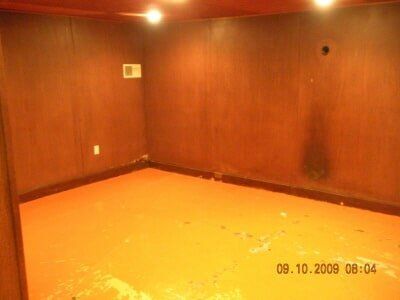 Empty wood-paneled room with orange carpet and recessed ceiling lights, dated 09.10.2009.
