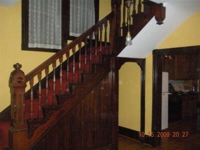 Wooden staircase with dark red banister in a yellow-walled interior hallway