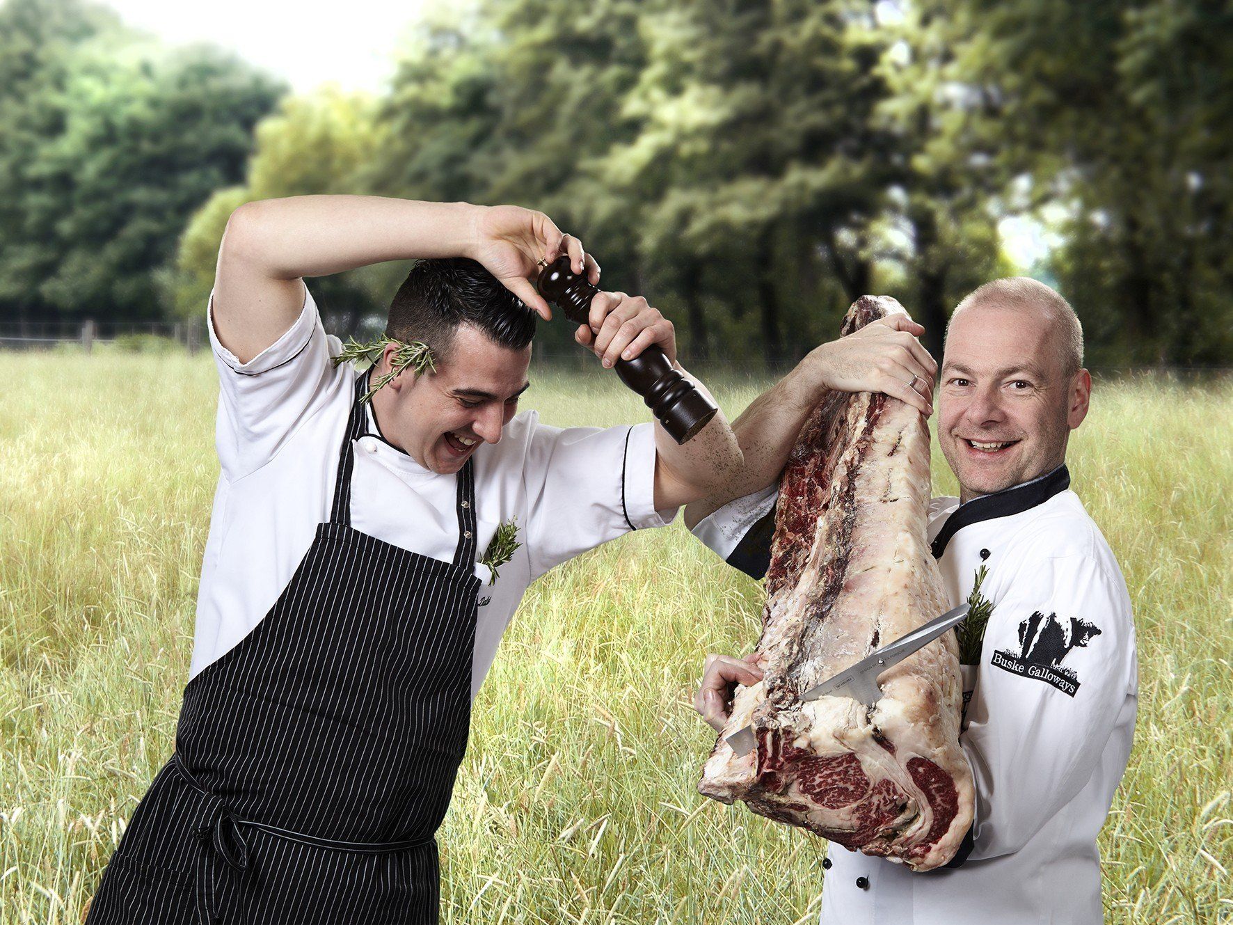 Zwei Männer stehen auf einem Feld und halten ein großes Stück Fleisch in der Hand.