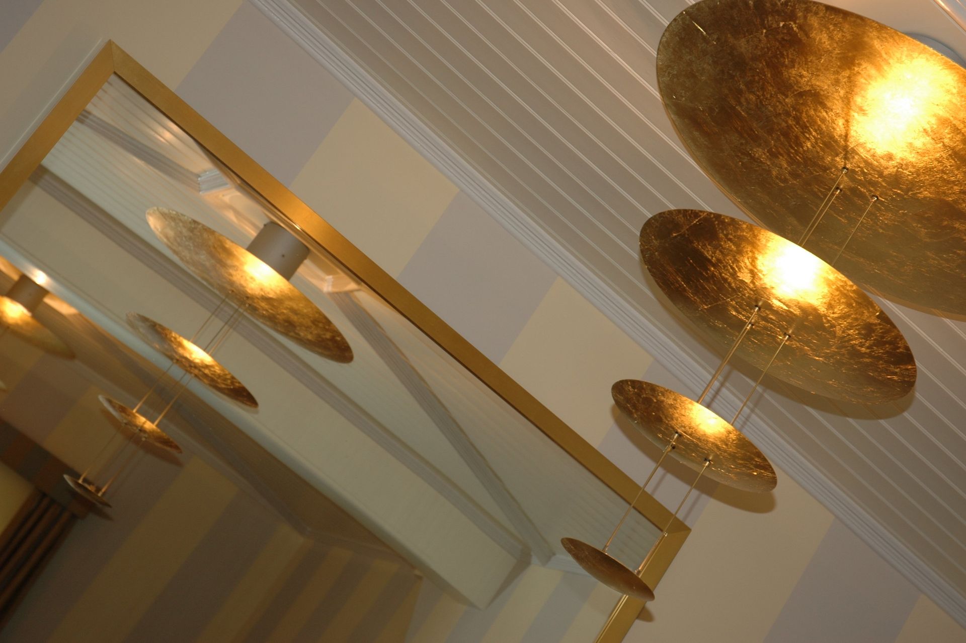 Eine Reihe goldener Pendelleuchten, die von der Decke hängen