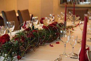 Ein langer Tisch mit einem Blumenstrauß und Weingläsern darauf