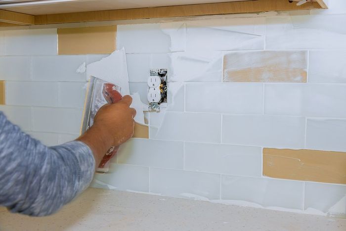 someone putting putty on the backsplash