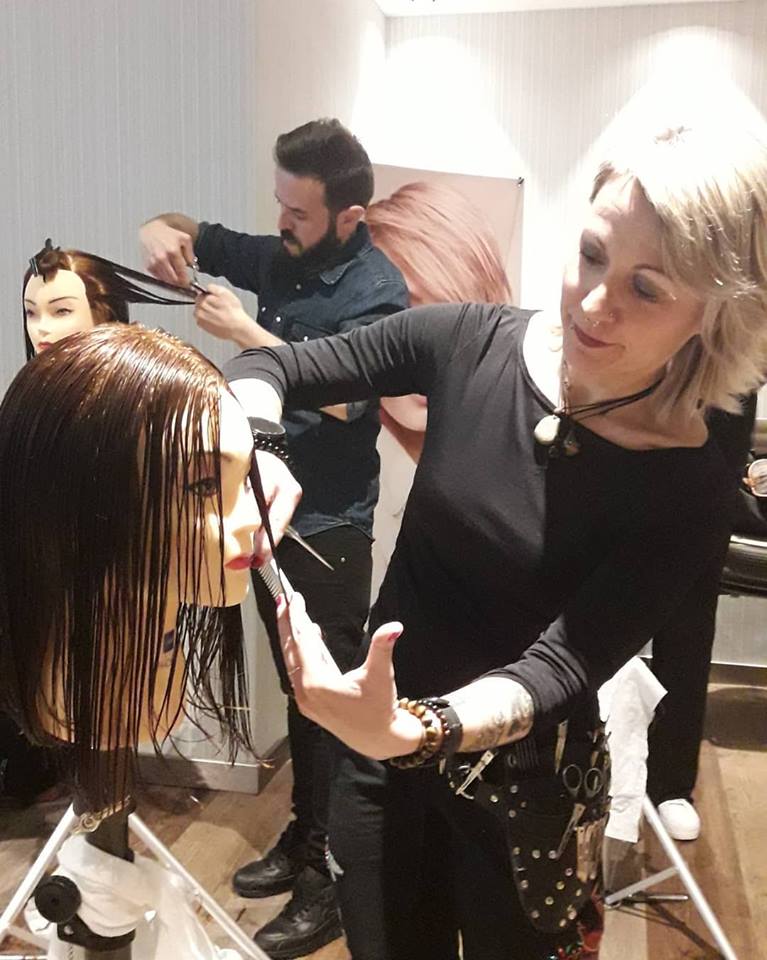 Dos peluqueros cortando el pelo en maniquíes en un salón de belleza.