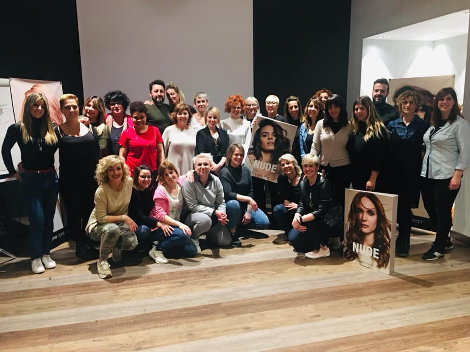 Grupo de personas posando frente a una pared en blanco y negro, sosteniendo retratos de una mujer.