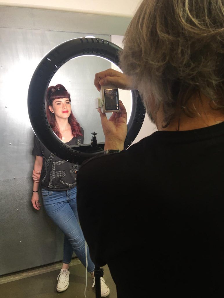 Una persona fotografía a una mujer pelirroja frente a un anillo de luz.