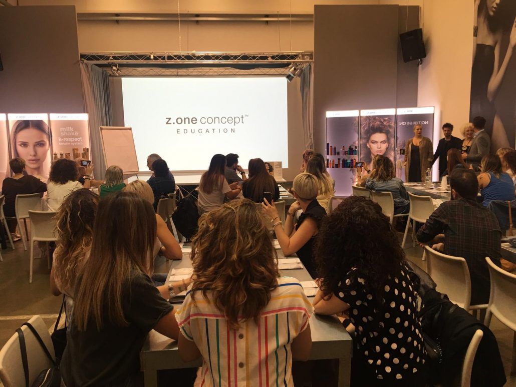 Taller con un grupo de personas sentadas en mesas, mirando una presentación en una pantalla.