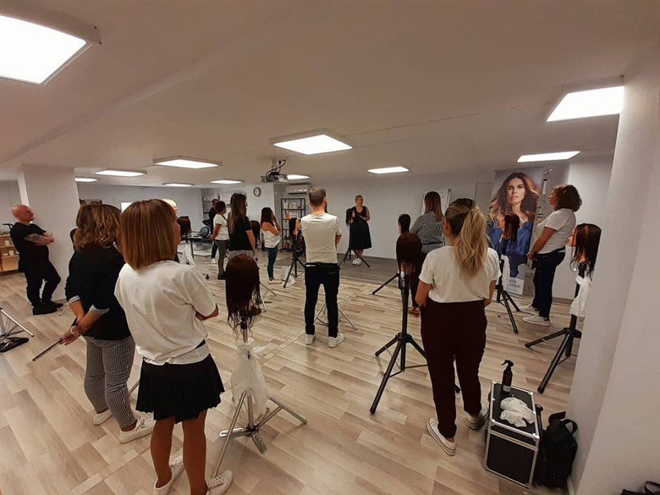 Clase de peluquería, los alumnos observan al instructor, maniquíes, sala luminosa.