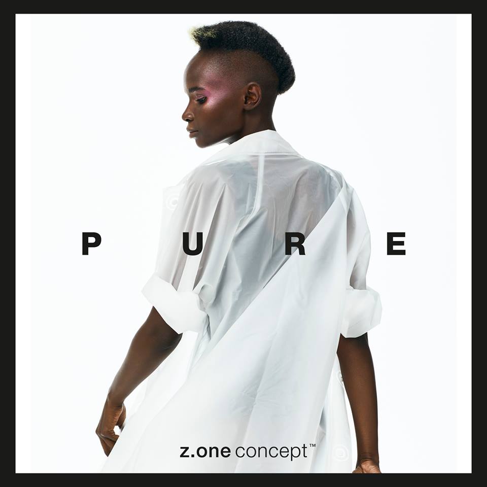Una persona con la cabeza rapada y una blusa blanca transparente posando en un estudio. Texto: PURO.