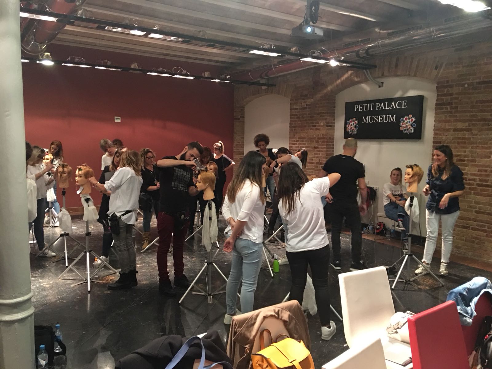 Clase de peluquería en sesión: los estudiantes practican el corte de cabello en maniquíes en una sala espaciosa.
