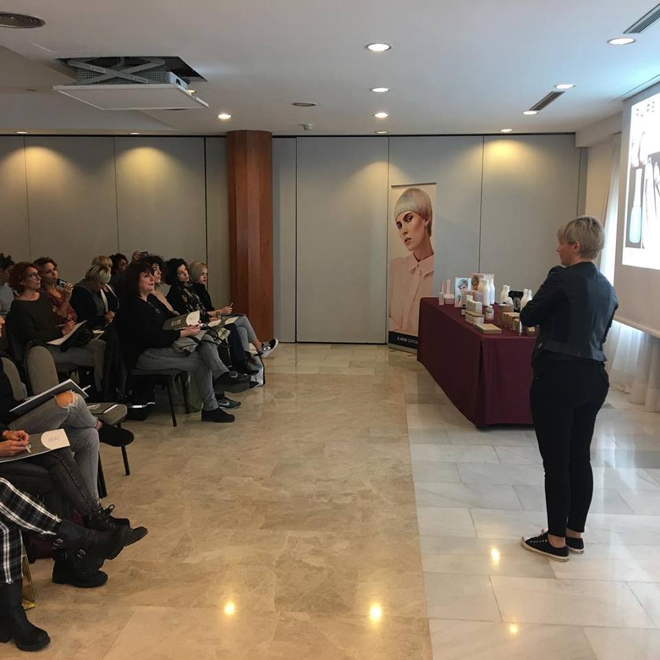 Una mujer dando una presentación en una sala de conferencias con una audiencia sentada.