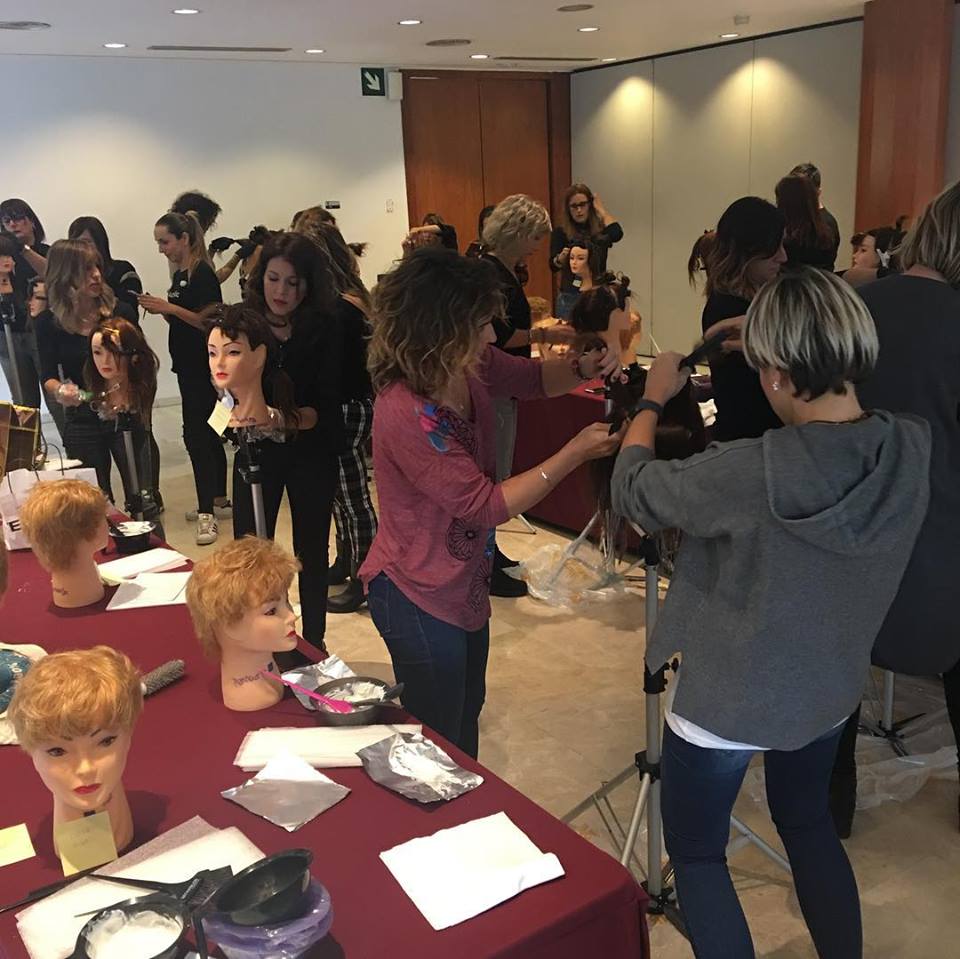 Estudiantes de peluquería en un aula, practicando el corte y el peinado en maniquíes.