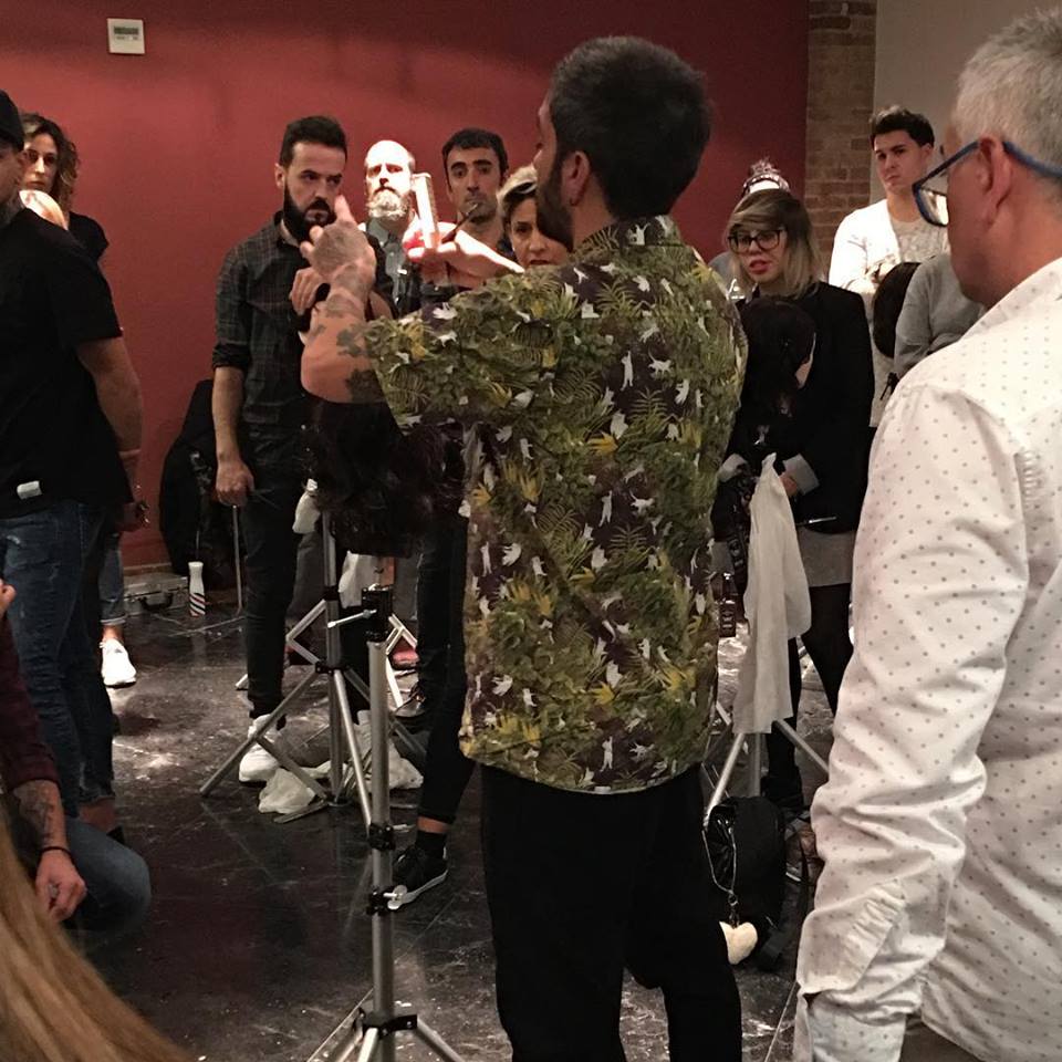 Un hombre con una camisa estampada demuestra cómo peinarse el cabello a un grupo en un taller.