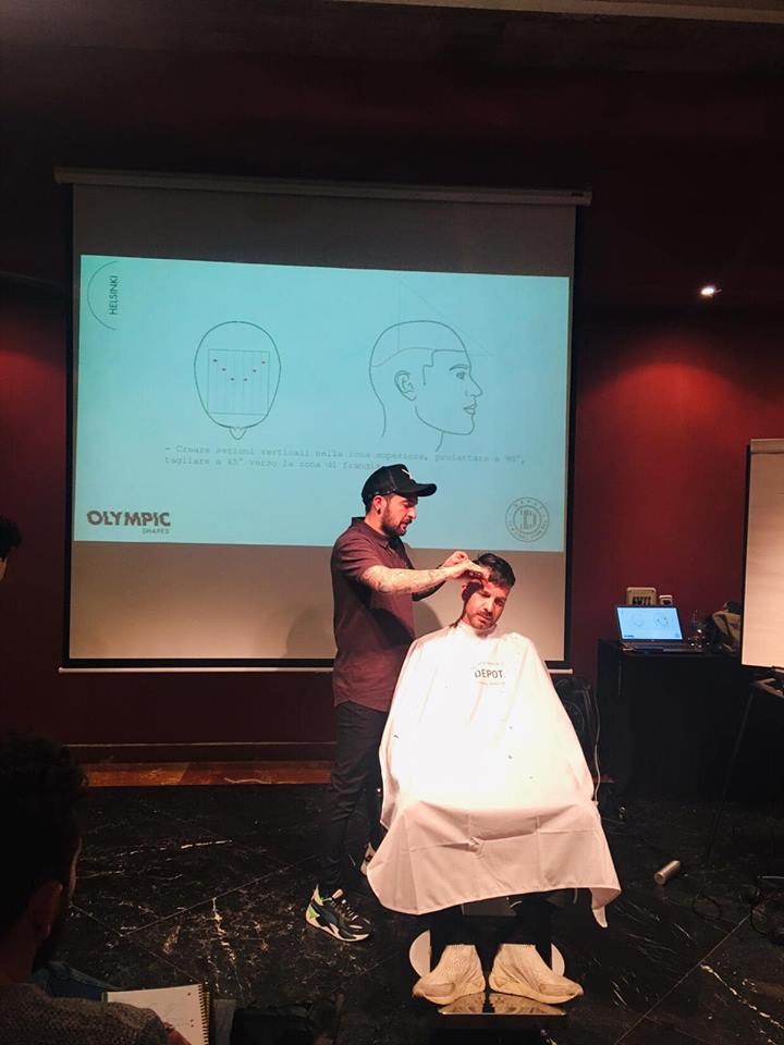 Un hombre hace una demostración de corte de pelo. Se proyectan diapositivas.